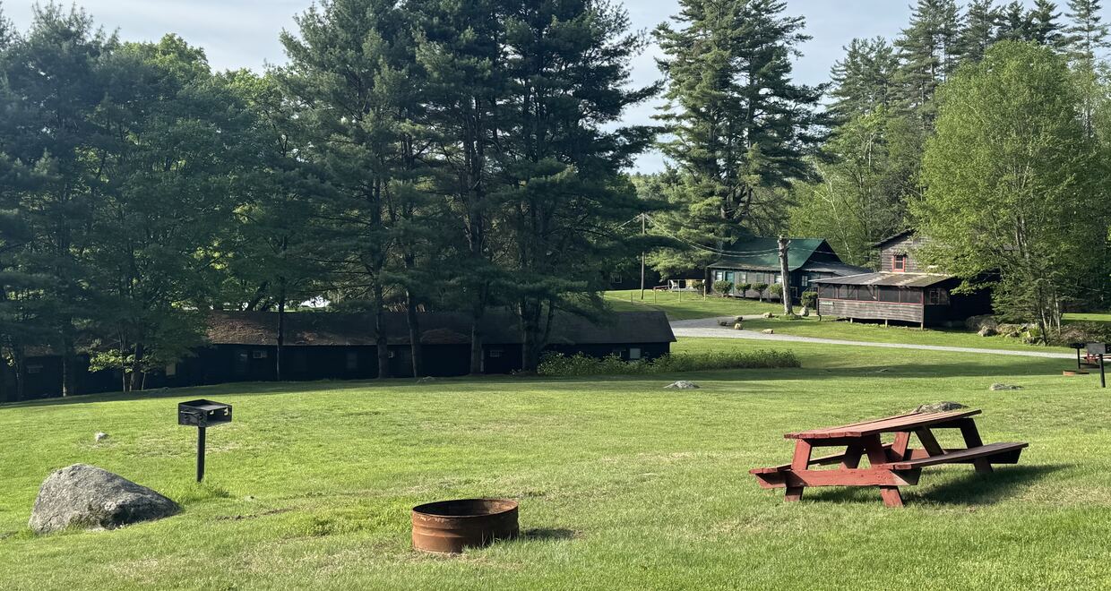Picnic table and fire pit on the lawn in front of the cottages at Twin Pines Resort